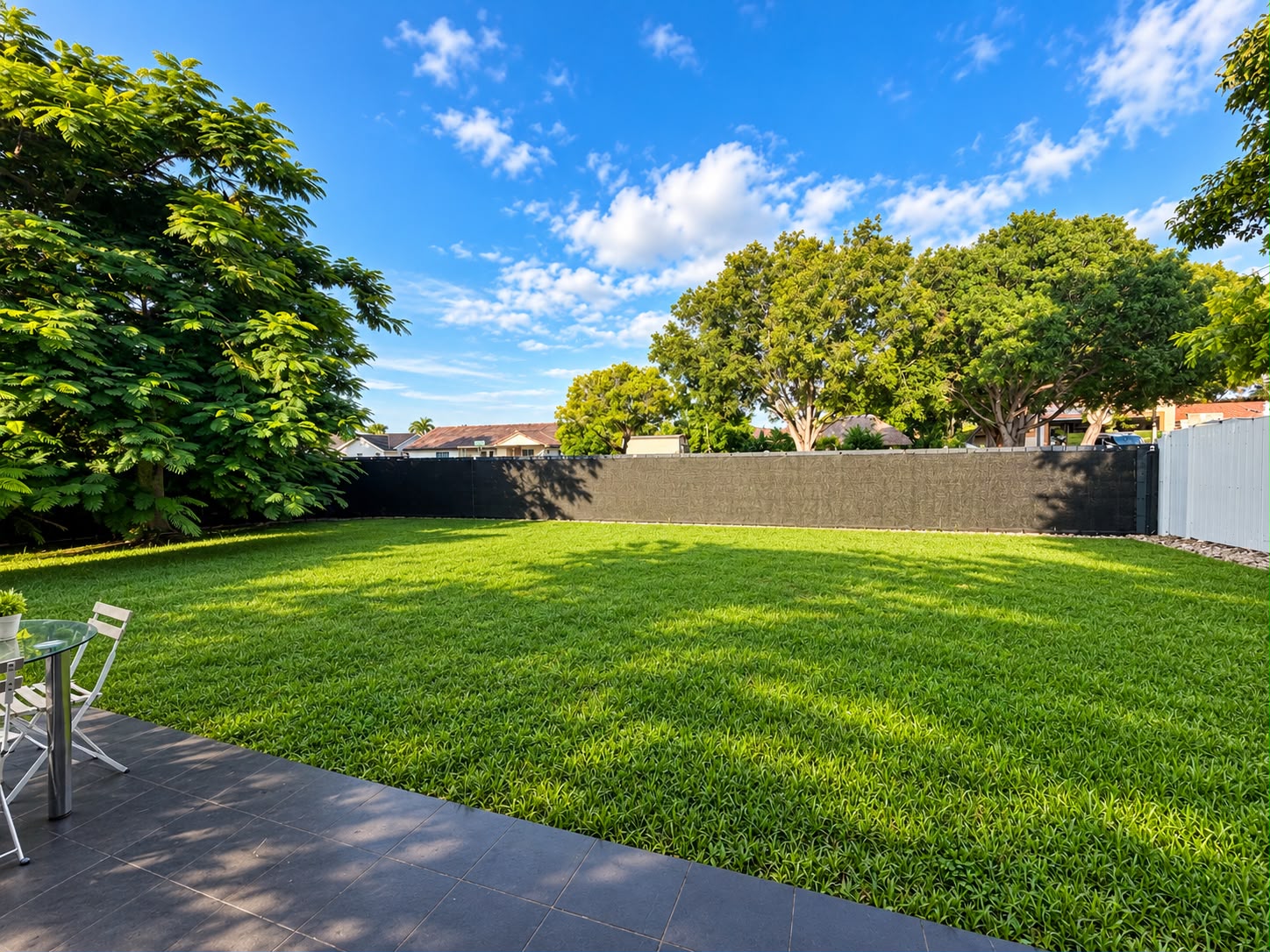 Fenced backyard with shade and open grass for dogs to run